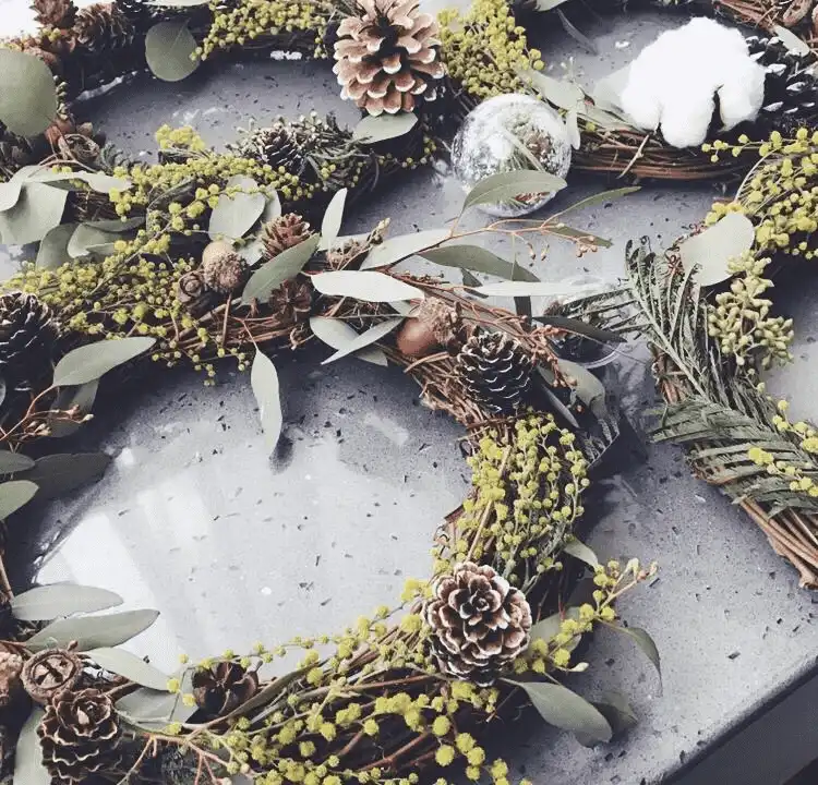 Handmade wreath made with pinecones, eucalyptus leaves, and twigs on a rustic table.